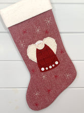 Christmas Angel, red plaid wool dress, off-white wool wings, off-white circular face, dress trimmed with vintage white buttons, red stitching outlining wings, white lace trimmed halo, light brown stitched eyes, pink blush on cheeks, angel hand appliquéd to red herringbone wool Christmas stocking, white and red hand stitched snowflakes, white natural cotton batting cuff