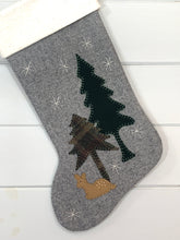 baby deer Christmas stocking, fawn Christmas stocking, stocking is gray herringbone wool fabric, fawn, pine trees are hand stitched to stocking, fawn is light brown wool fabric with white stitched spots on its back, tall pine tree is dark green wool fabric, short pine tree is green plaid wool fabric, white snowflakes are hand stitched onto stocking, cuff is white natural cotton batting, woodland Christmas stocking, baby deer rustic Christmas stocking